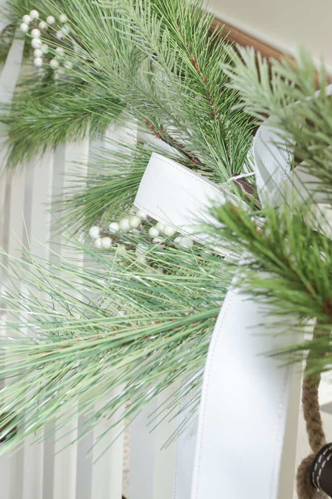 Closeup detail of Magnolia Hearth and Hand faux garland with white berries and tied with a 2 inch white ribbon.