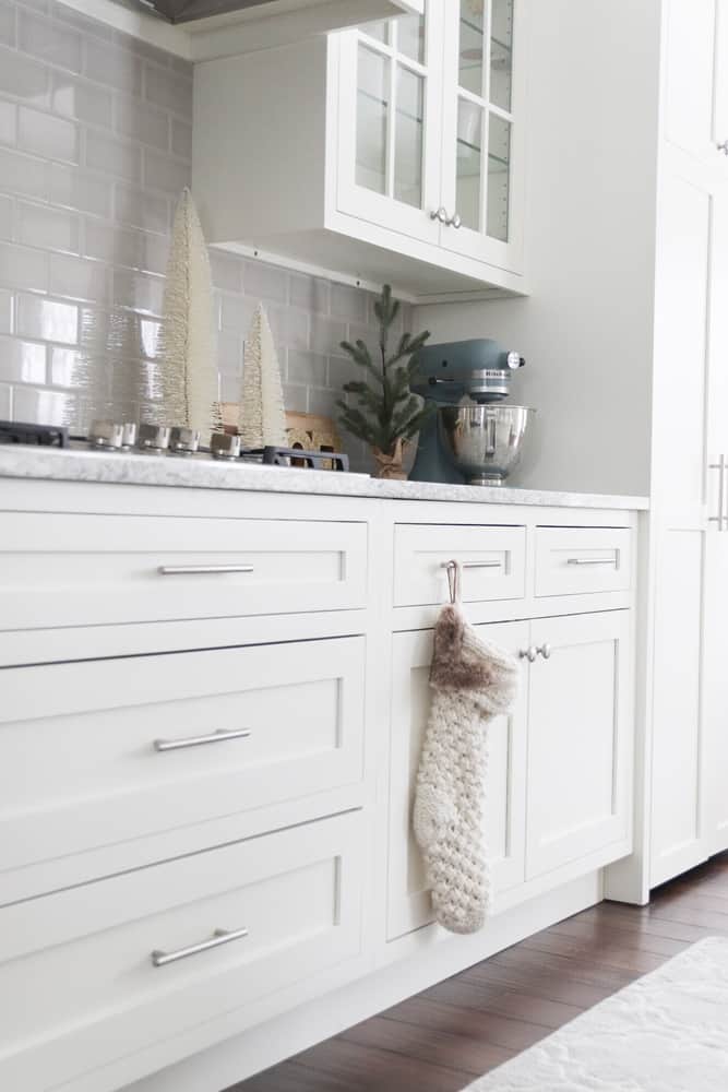 White kitchen with grey subway tile backsplash and neutral textured Christmas decor.