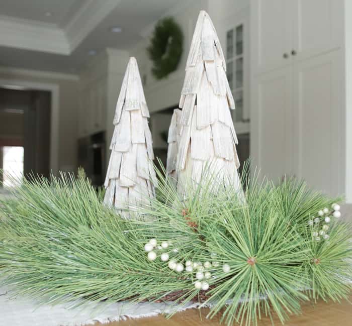 Faux wreath with wooden Christmas trees decorating white kitchen.