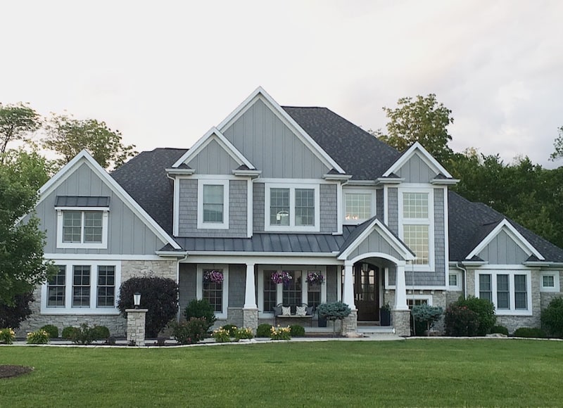 Grey shake shingle two story home with board and batten and stone.
