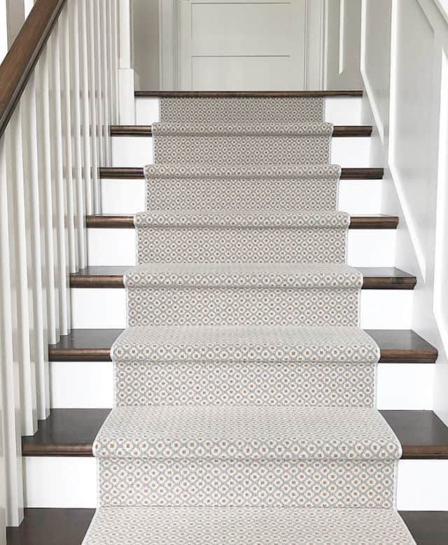 Patterned stair runner in blue and cream on wood tread stairs with white risers.