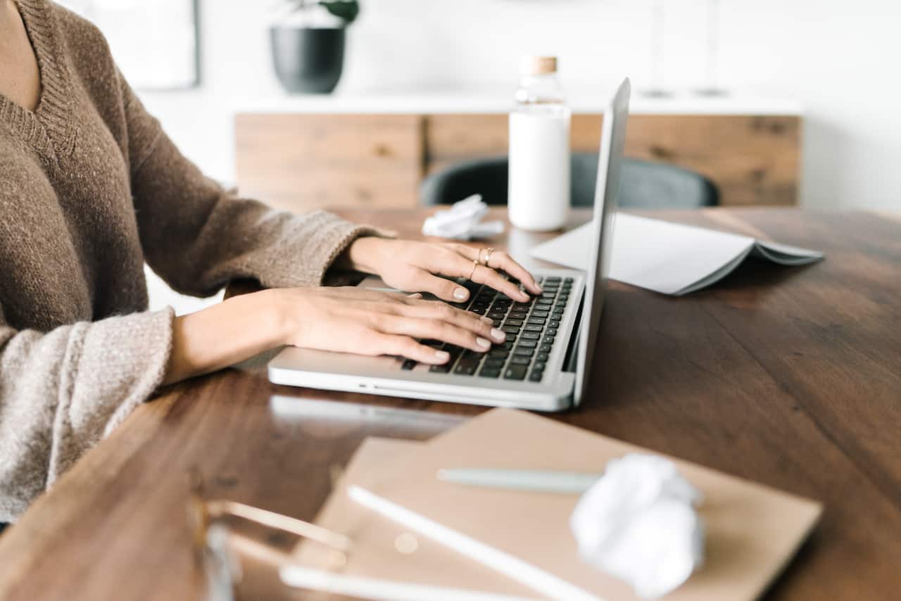 Image of a woman's hands at a laptop typing the 5 Steps to Prepare for a Successful Home Build FI