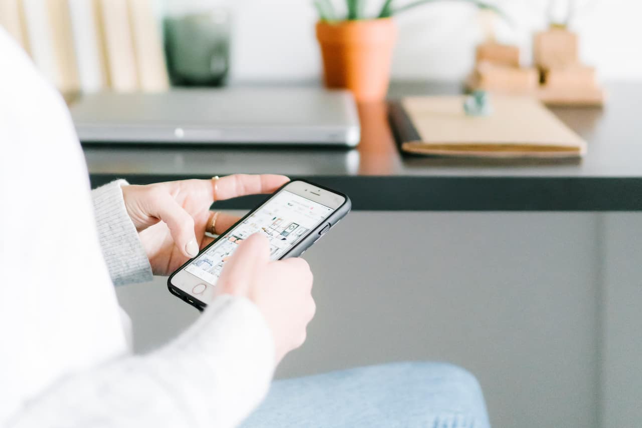 Woman looking at social media on phone as example of Caroline on Design Top Pinterest Boards