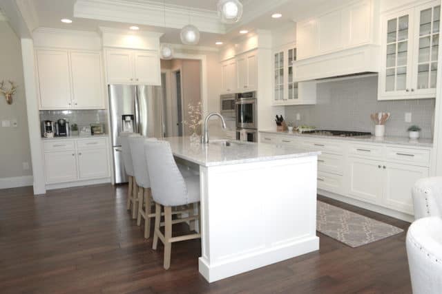 open kitchen with large island, white cabinets, and grey subway tile backsplash