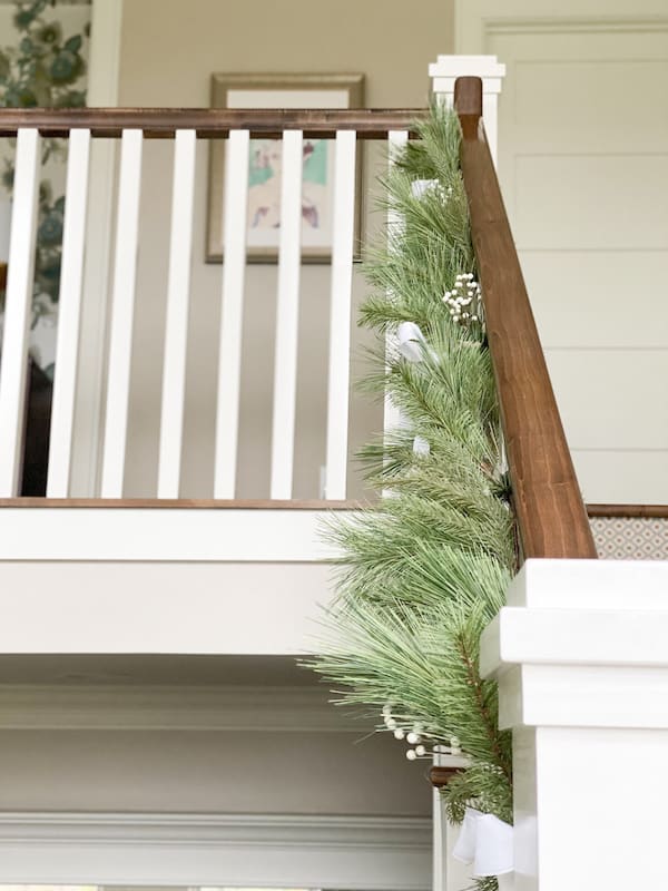 faux garland on stair railing with white ribbon