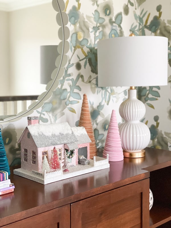 cody foster christmas village with velvet cone christmas tress on wood cabinet with white lamp, floral wallpaper, and white mirro