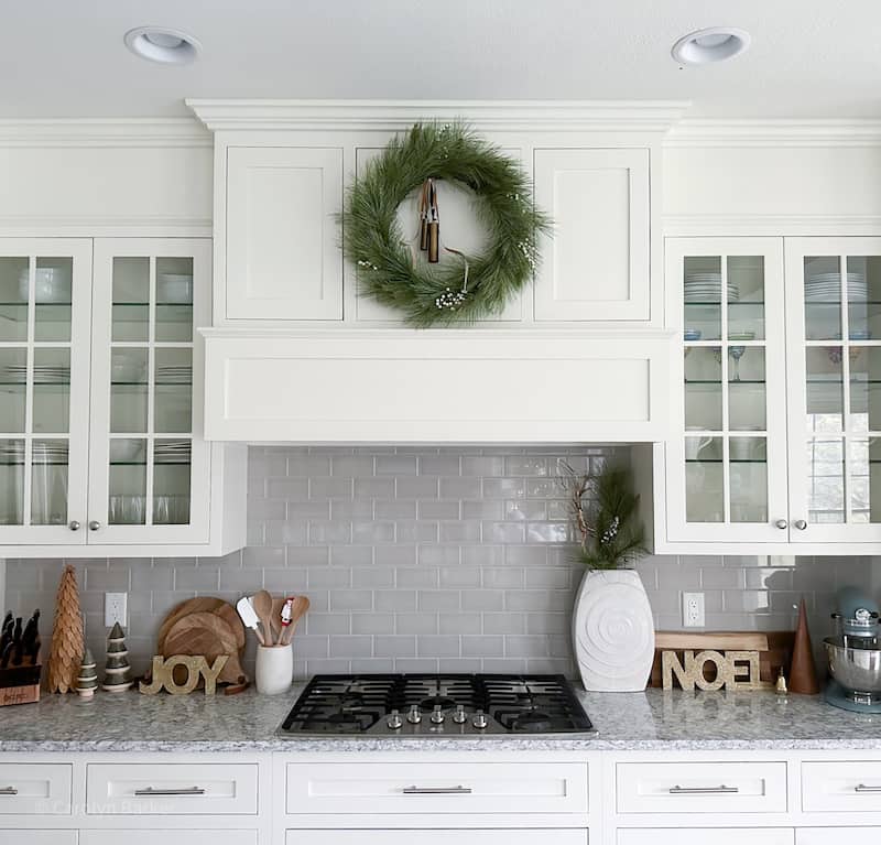 white kitchen cabinets with grey subway tile backsplash and christmas decorations.