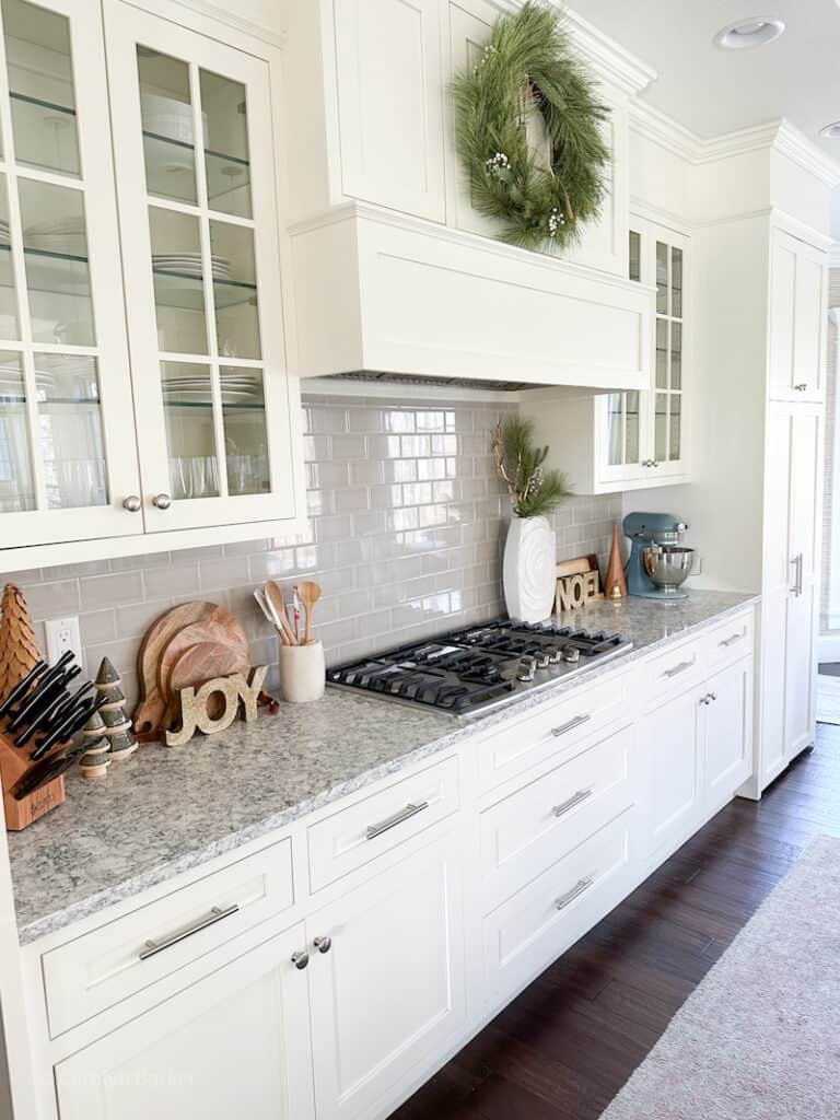 white kitchen cabinets with grey subway tile backsplash and christmas decorations.